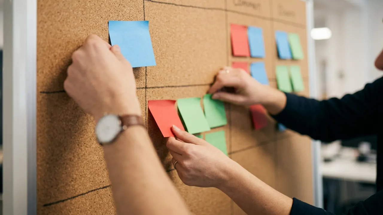 Hands of two different people moving colored cards on one shared board